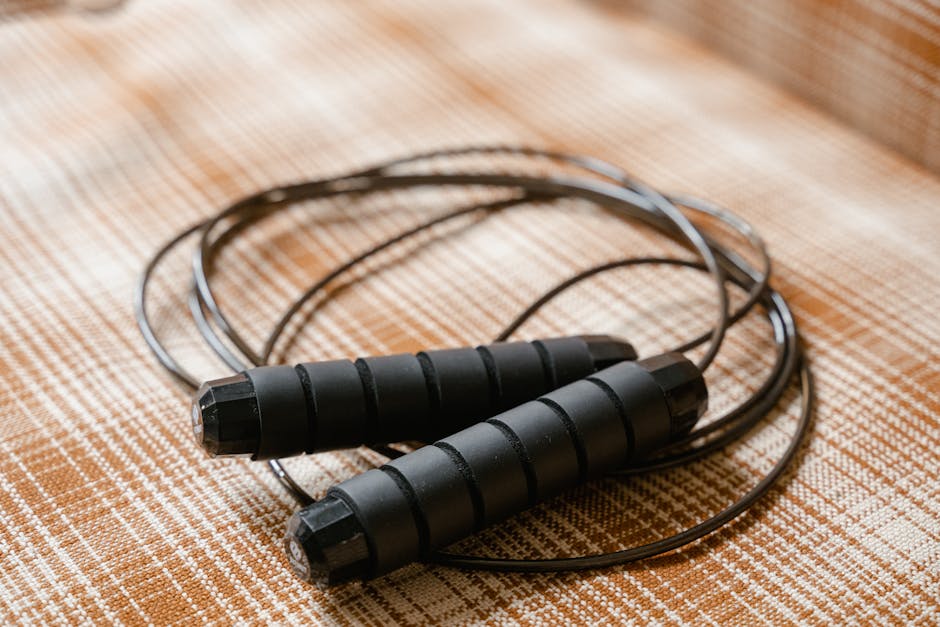 A black jump rope coiled on a patterned plaid surface, highlighting fitness equipment.