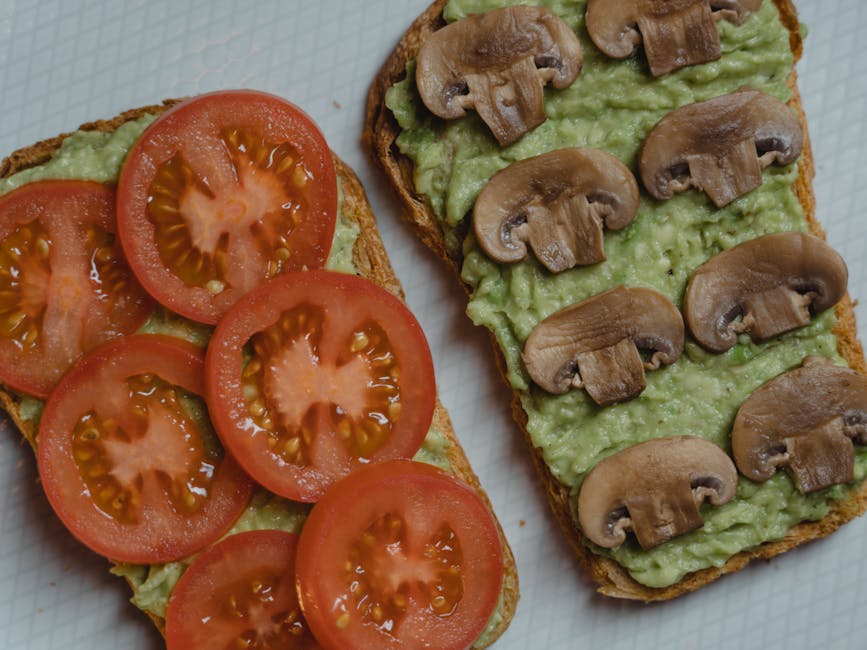 Top view of delicious vegan sandwiches with avocado, mushrooms, and tomatoes on a light background.