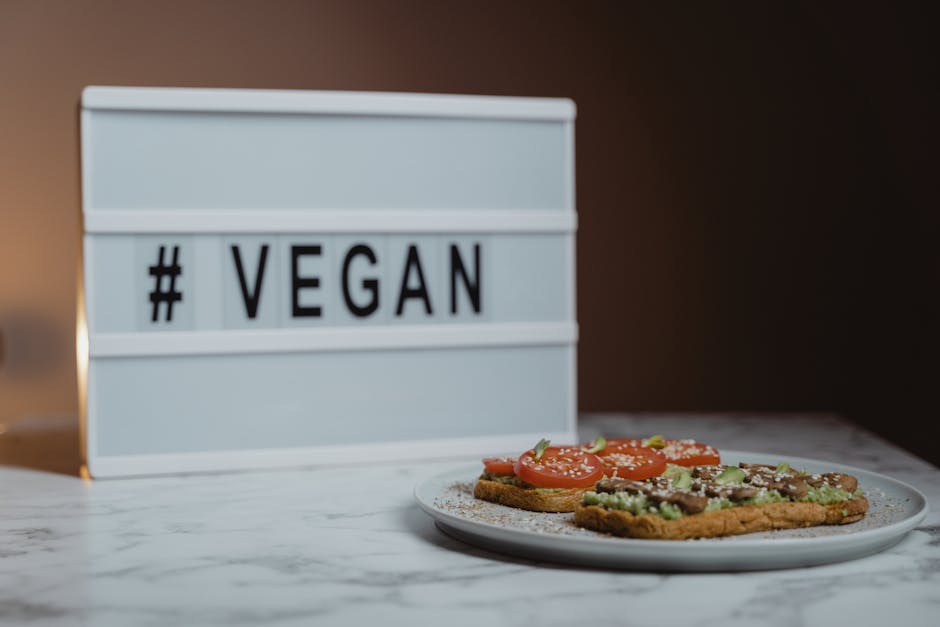 Delicious vegan avocado toast with tomatoes on marble table beside vegan sign.